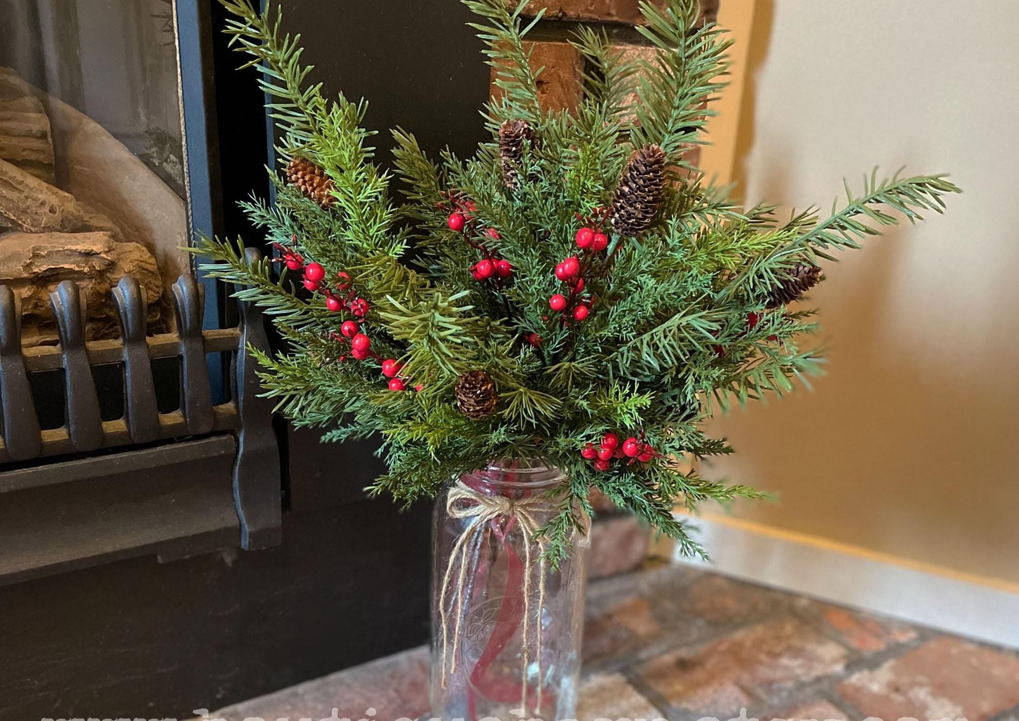 Christmas greenery stems with red berries and pinecones in rustic holiday arrangement