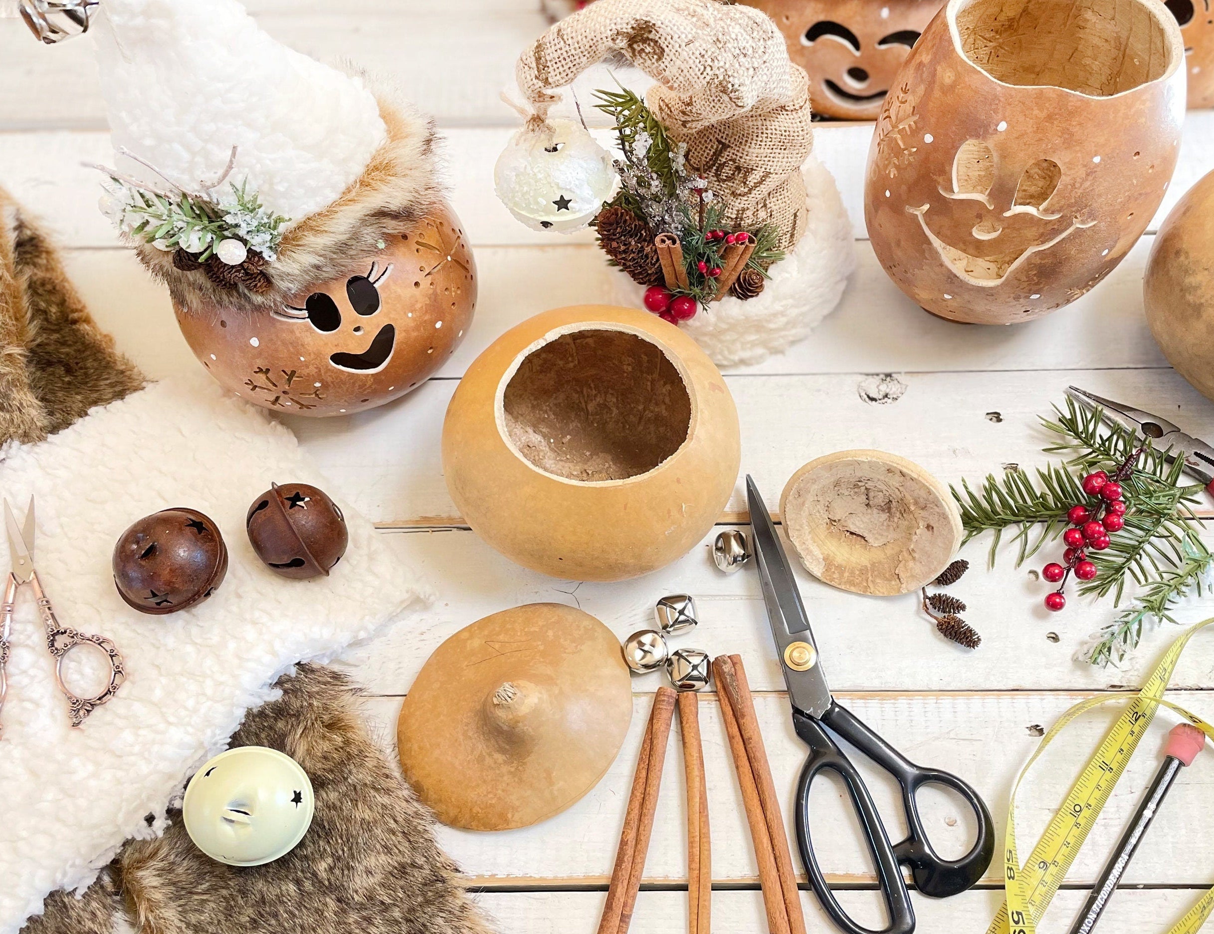 Decorative gourds with face designs on a wooden surface with tools and decorations.