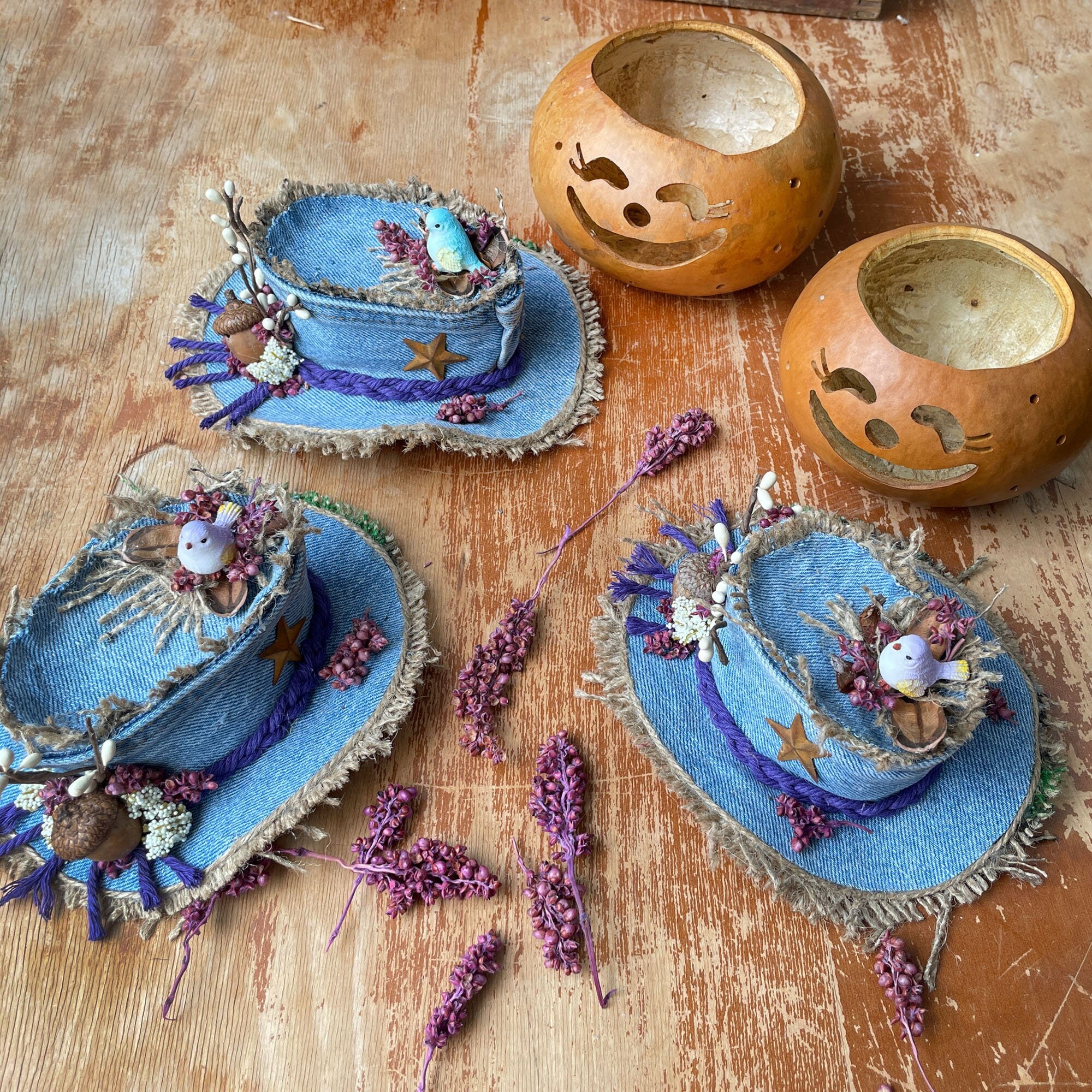 Decorative blue hats with floral embellishments on a wooden surface with wooden bowls.