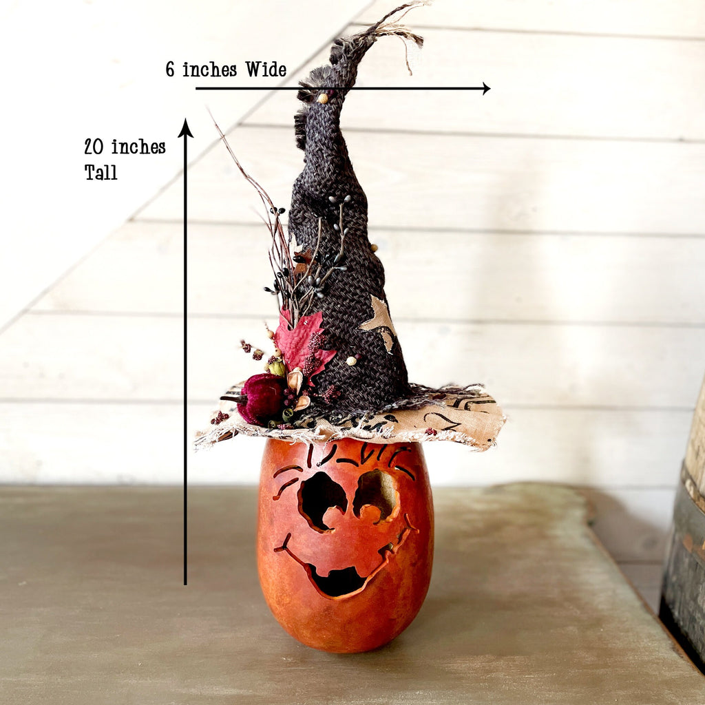 Decorative pumpkin with a witch hat on a wooden surface