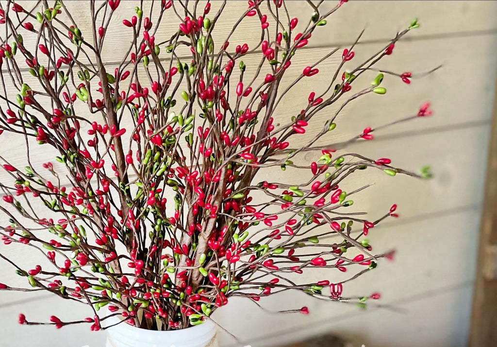 Bouquet of red and green flowers in a white vase on a light background