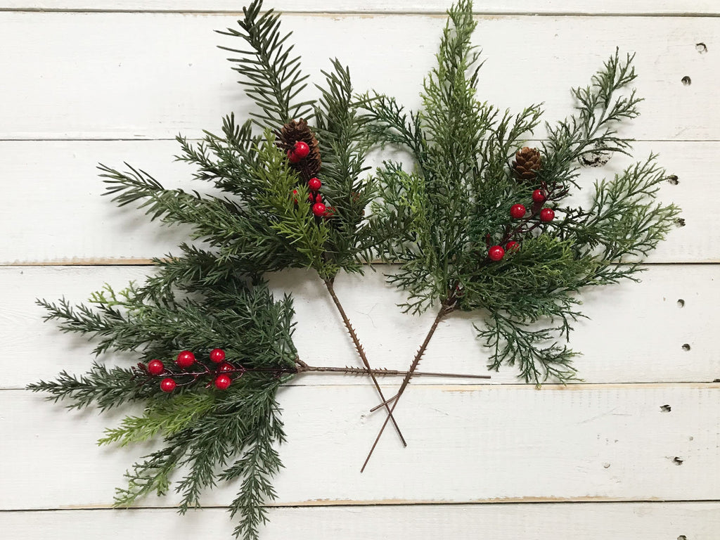 Greenery with red berries on a white wooden surface
