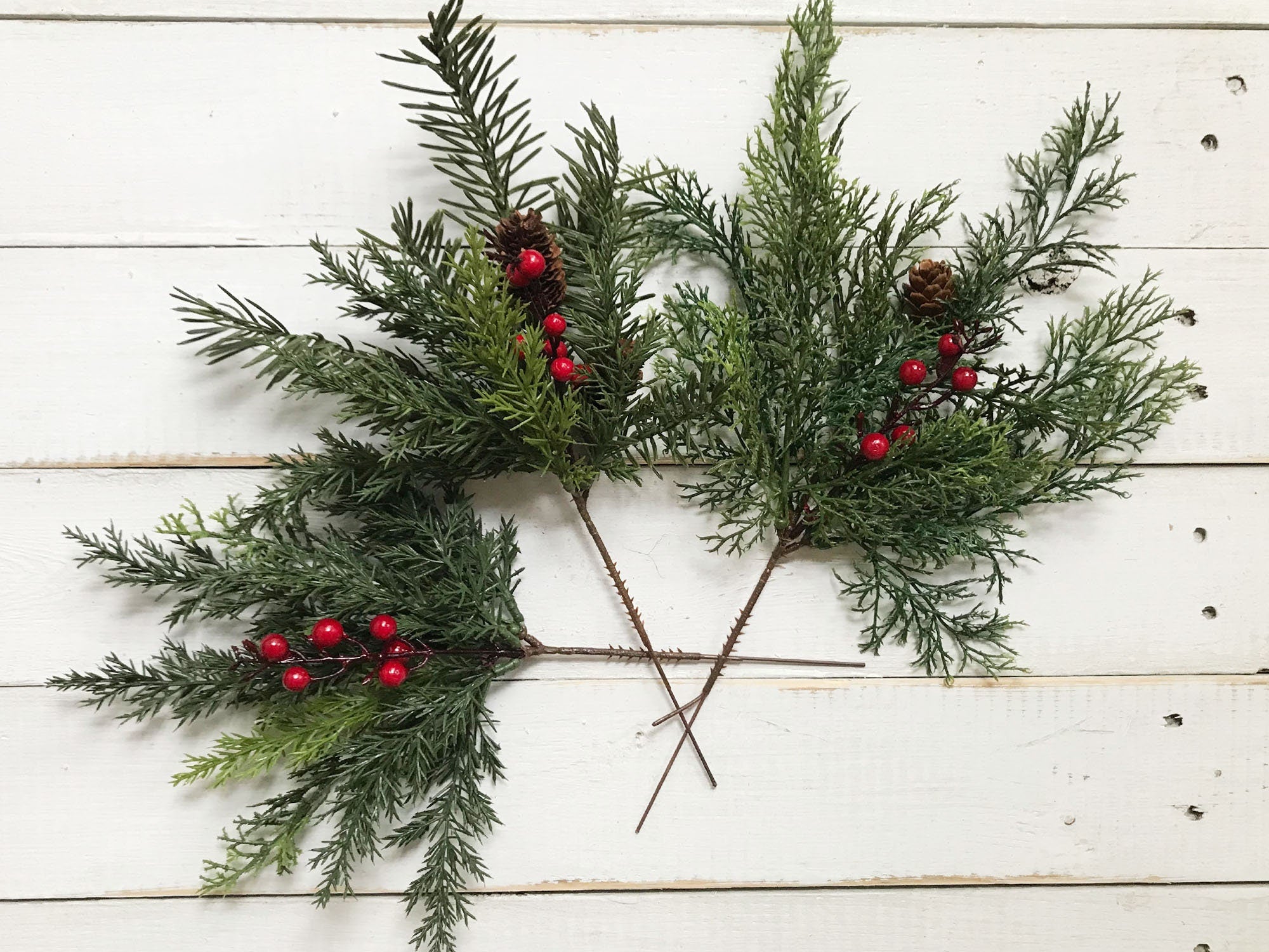 Greenery with red berries on a white wooden surface