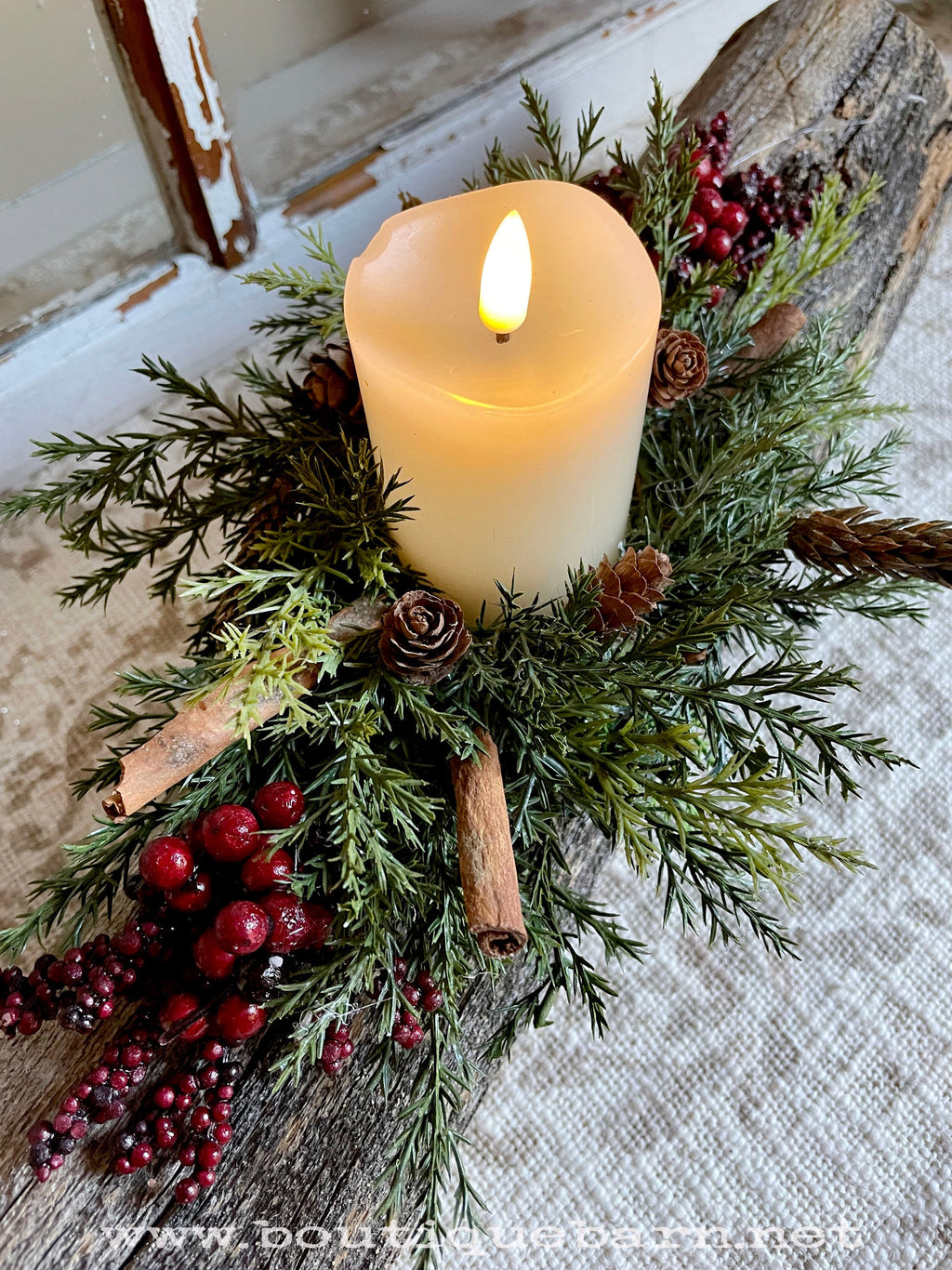 Decorative candle arrangement with greenery and berries on a rustic surface