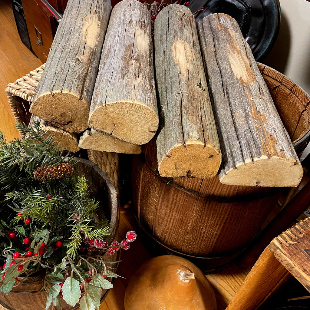 Wooden logs stacked on a wooden surface with Christmas decorations.