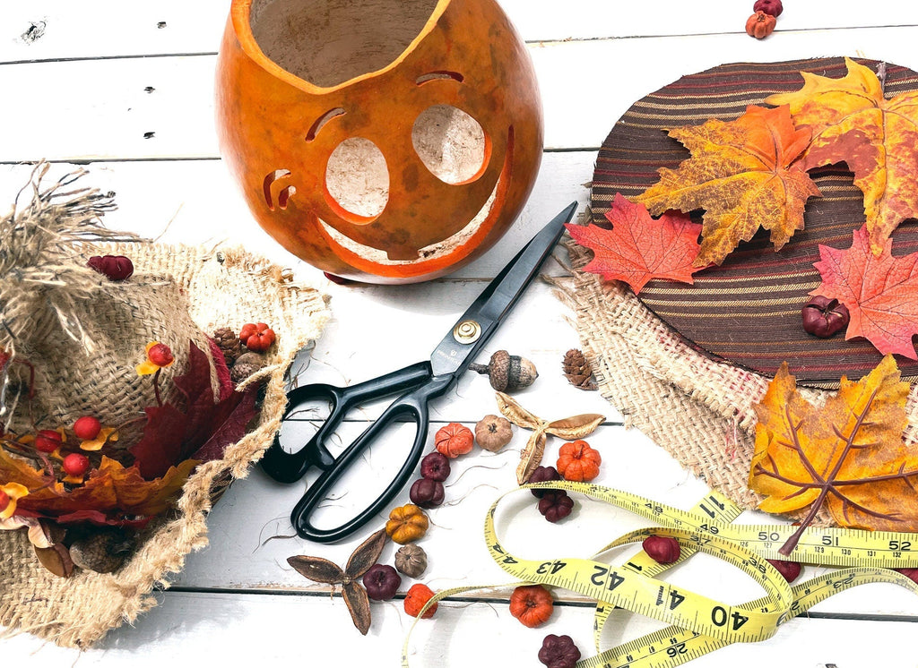 Autumn-themed decor items including a pumpkin, leaves, scissors, and a tape measure on a wooden surface.