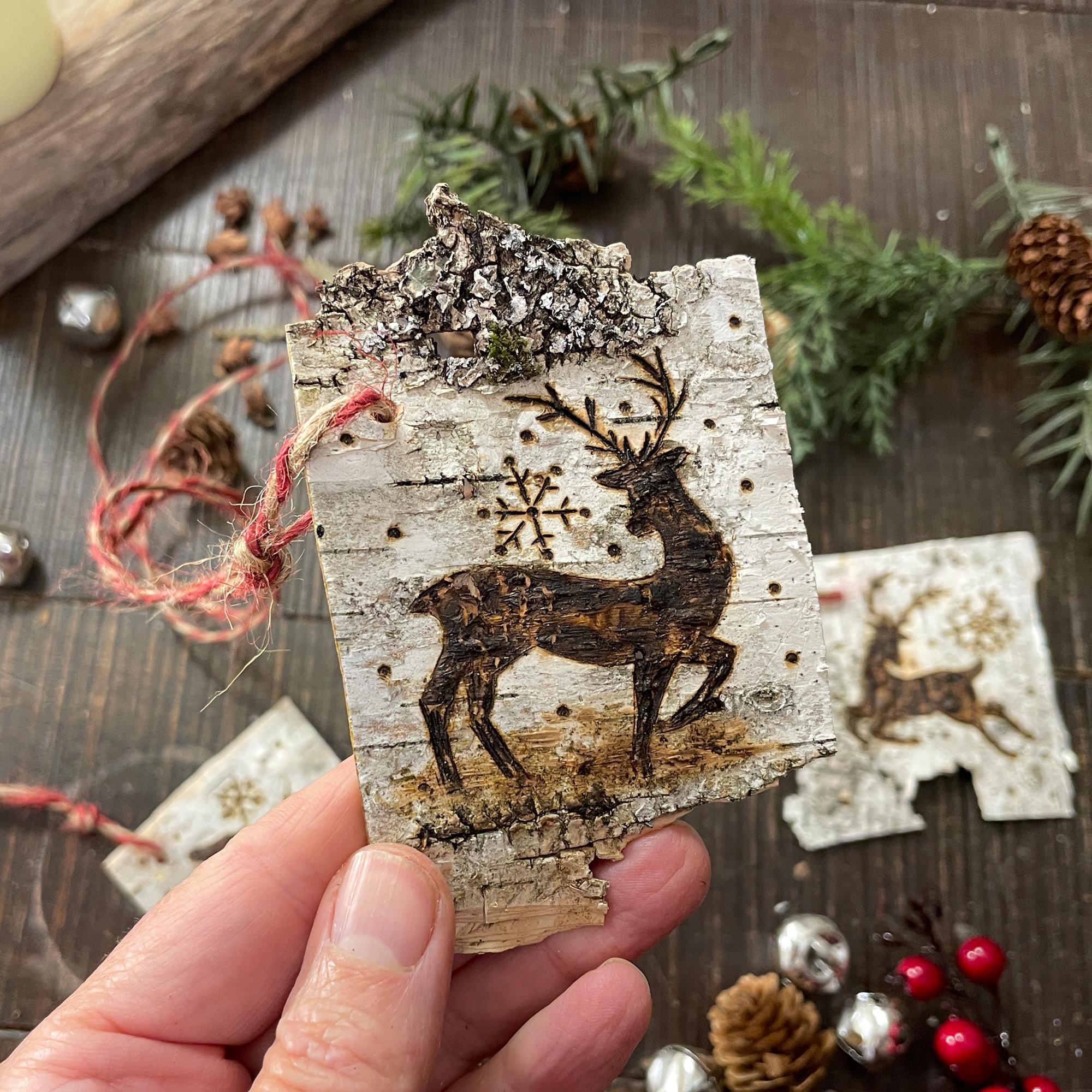 Hand holding a wooden ornament with a deer design on a rustic background
