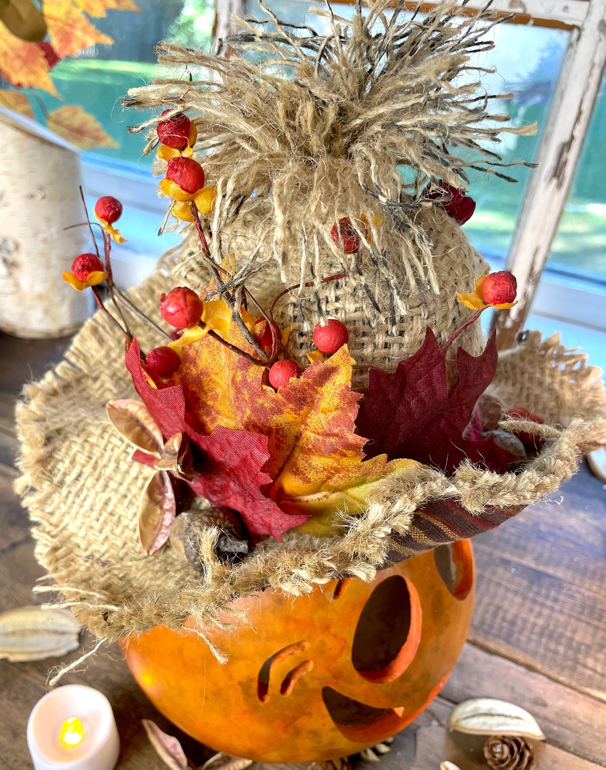 Decorative fall arrangement with pumpkins, leaves, and berries on a wooden surface.