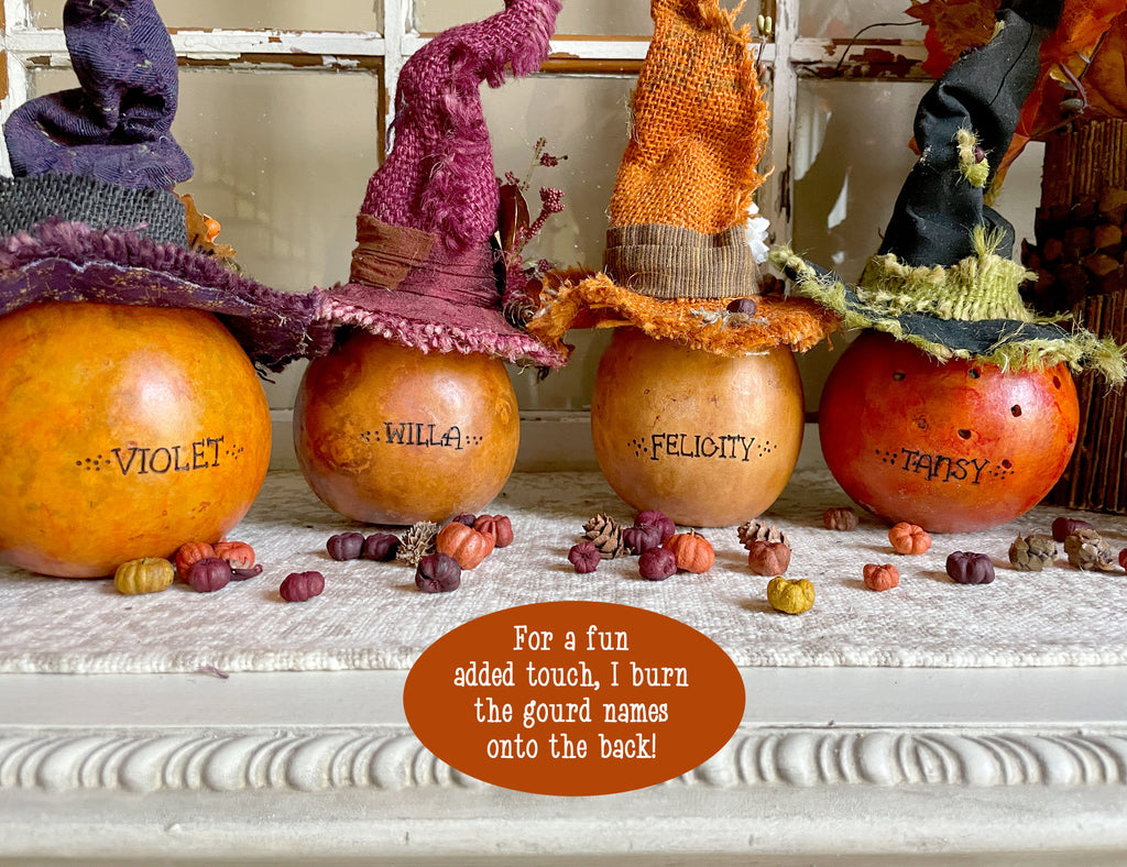 Decorative pumpkins with witch hats and names on a mantel.