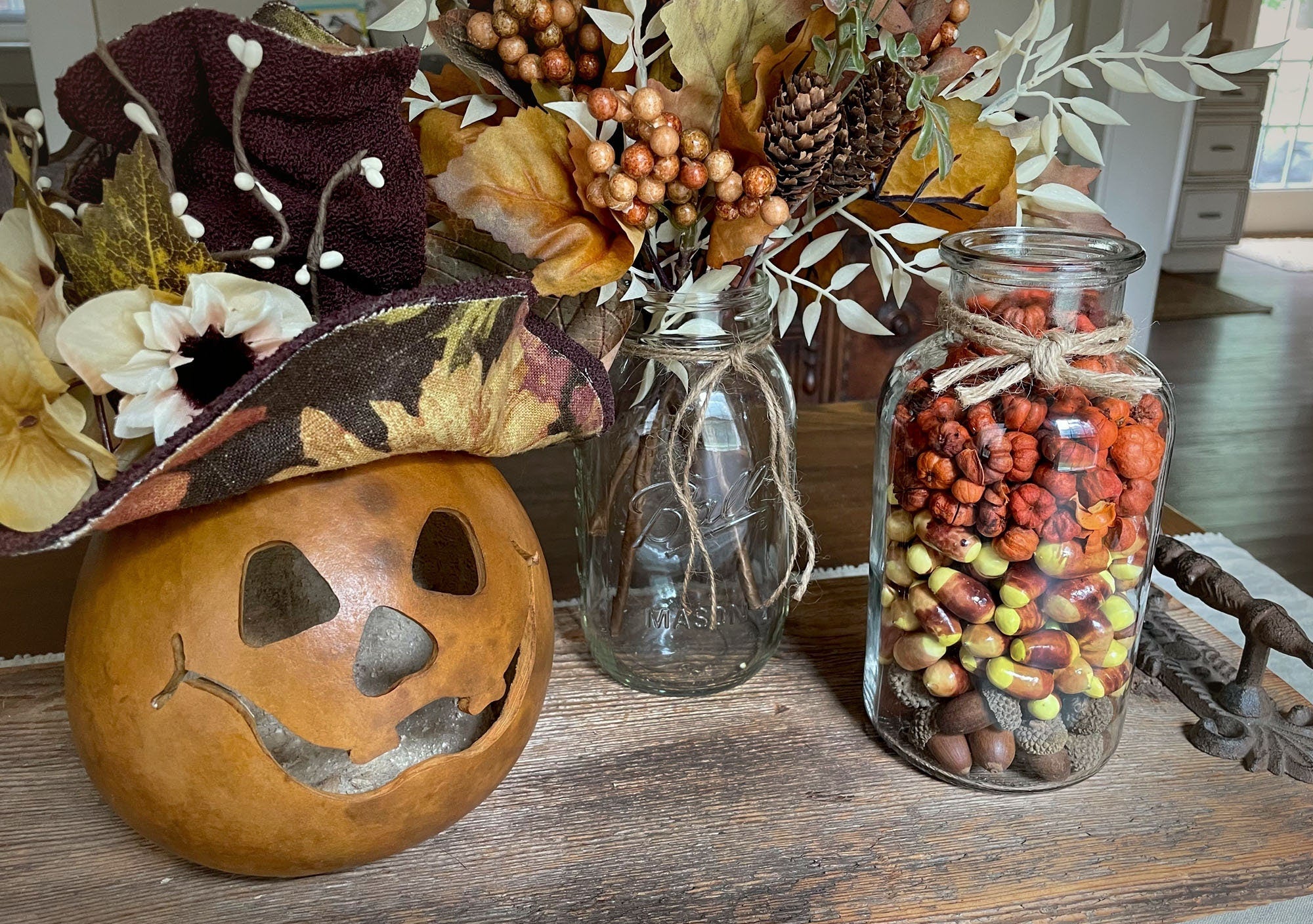 Autumn-themed decor with pumpkins, mason jars, and fall leaves on a wooden surface.