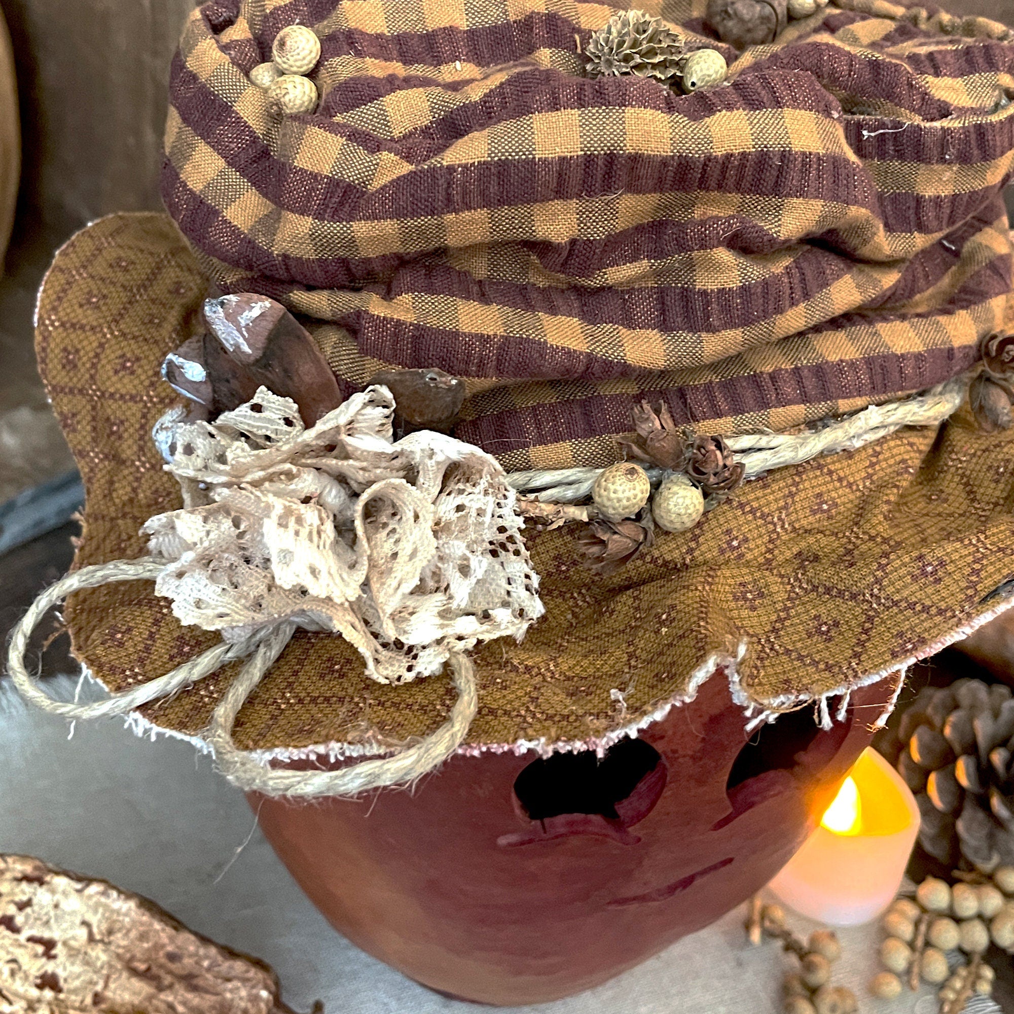 Decorative pumpkin with a plaid fabric hat and natural elements on a neutral background