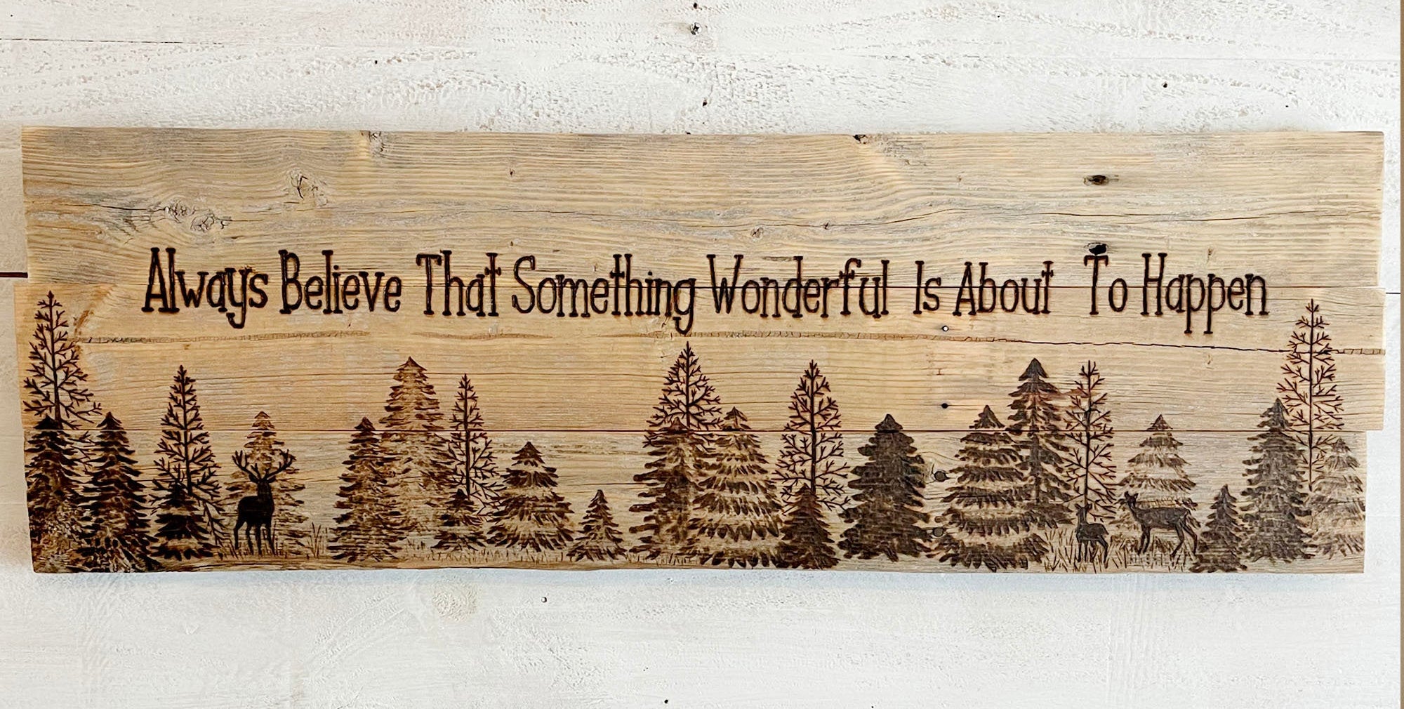 Wooden sign with nature design and motivational quote on a white wooden background, featuring the website 'www.boutiquebarn.