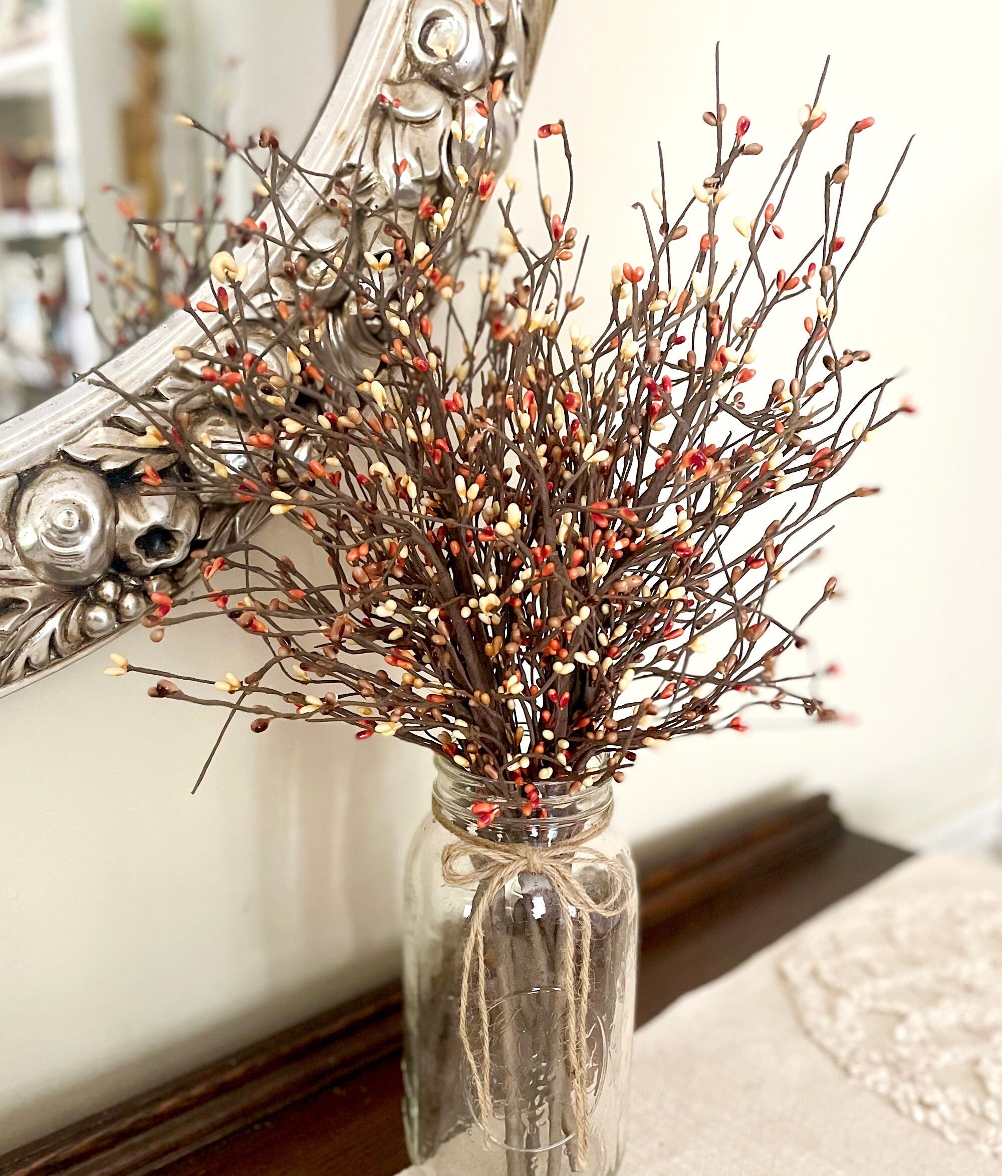 Clear glass vase with decorative branches against a mirror background