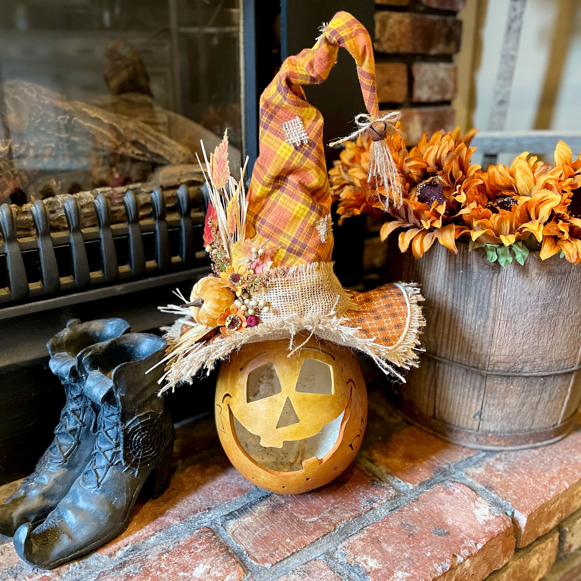 Decorative Halloween setup with a jack-o'-lantern, boots, and autumn-themed decorations on a stone surface.