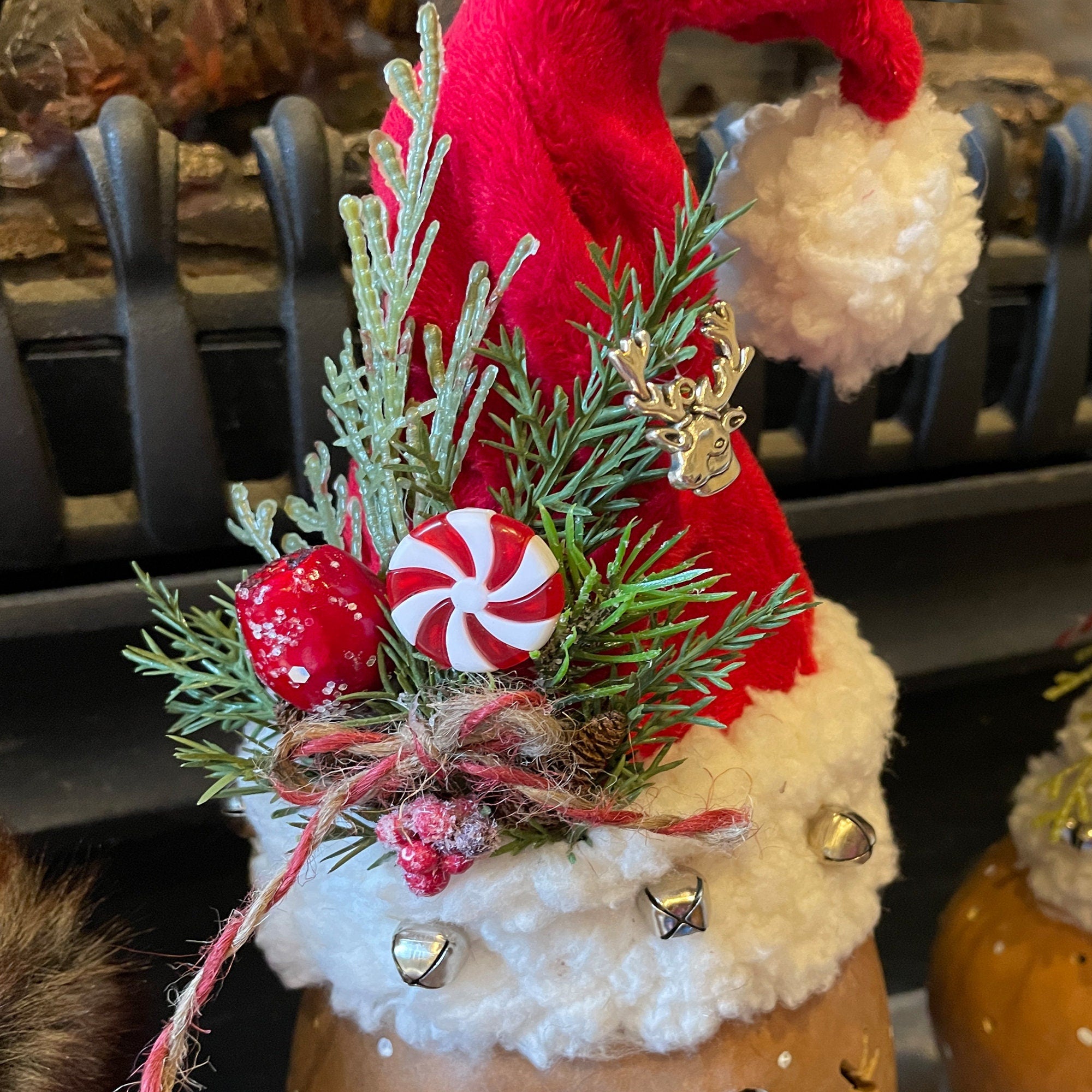 Decorative Christmas gnome with red hat, greenery, and candy on a blurred background