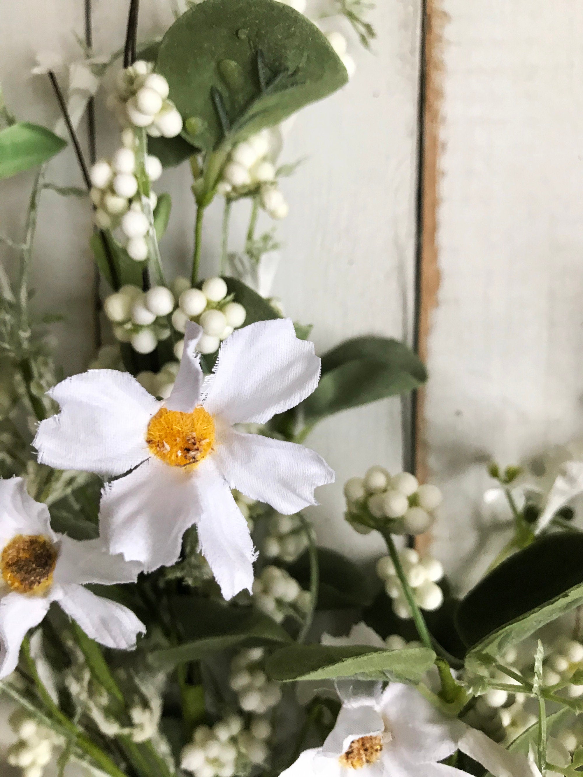Artificial flowers with white petals and green leaves on a neutral background