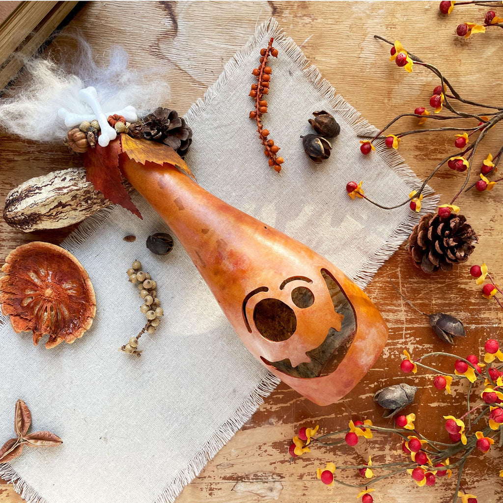 Decorative gourd with a face on a wooden surface with autumn elements