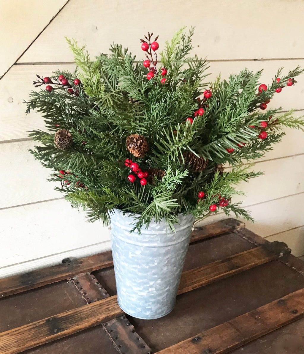 Potted plant with greenery and red berries on a wooden surface