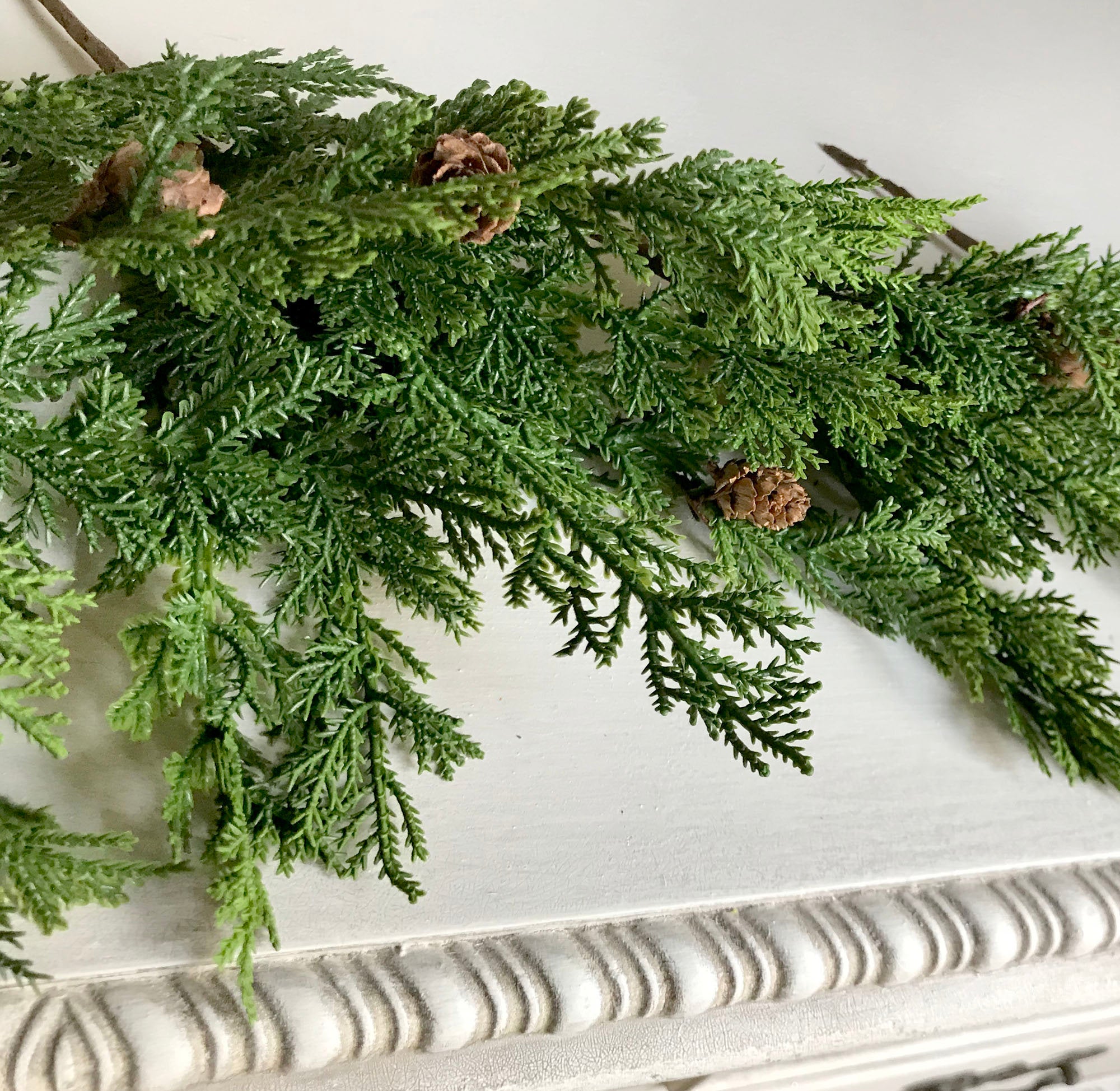 Green artificial evergreen garland on a decorative surface