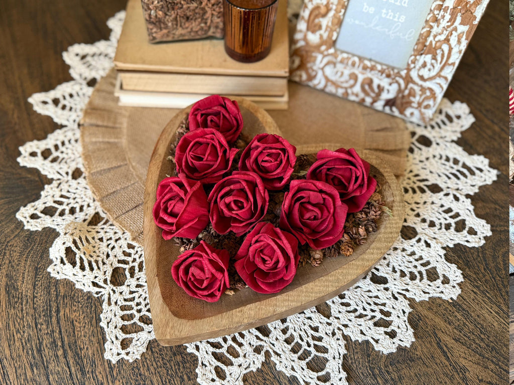 Heart-shaped wooden box with red roses on a lace doily