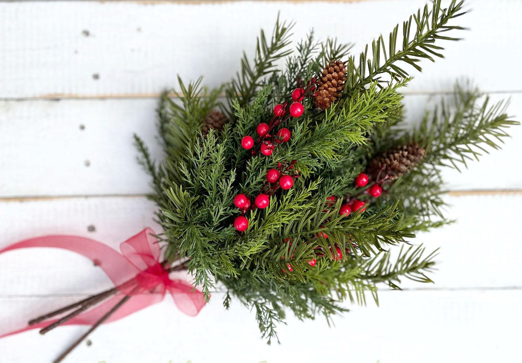 Christmas wreath with red berries and pine cones on a white wooden background
