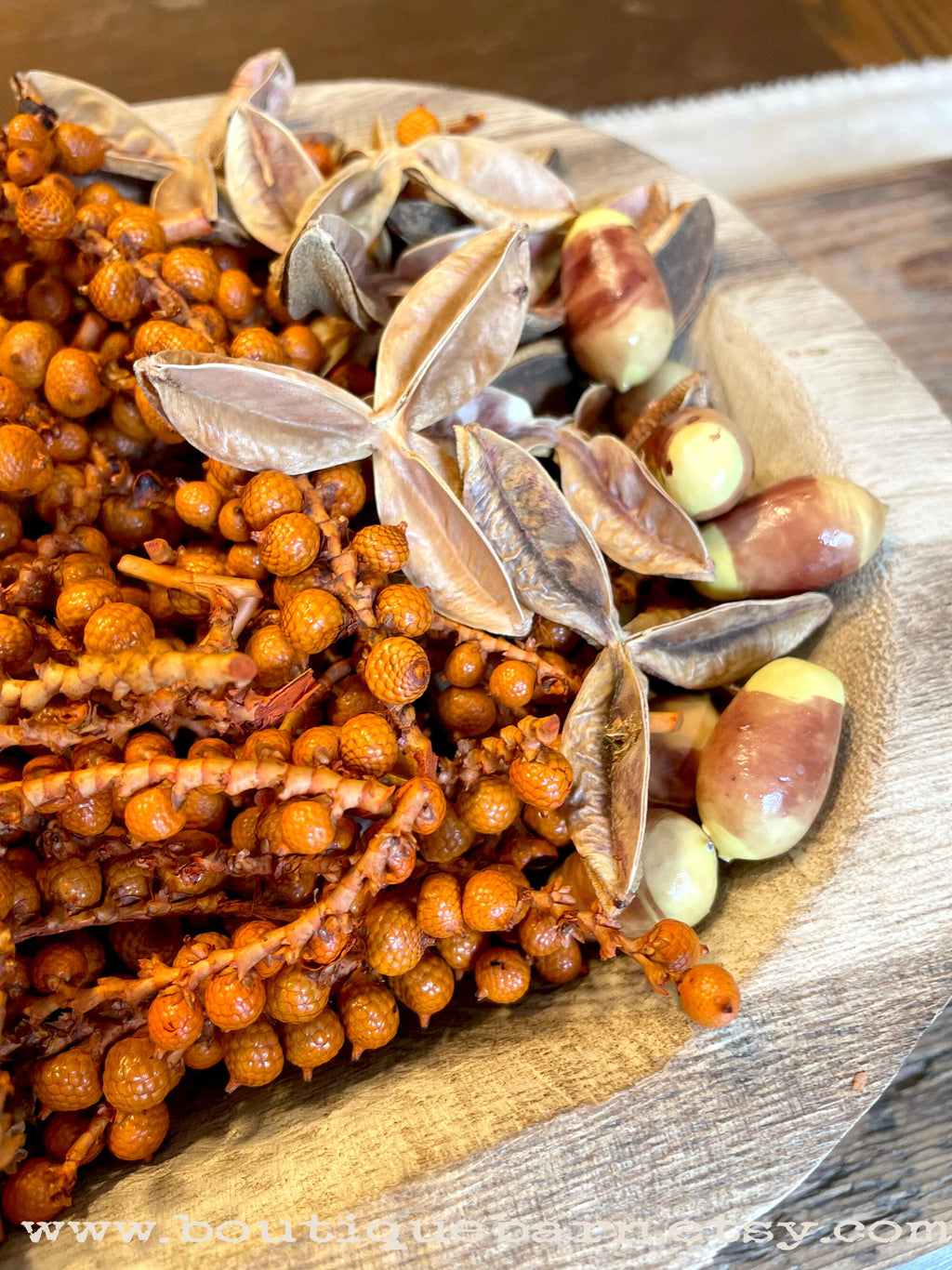 Decorative arrangement of dried berries and seeds on a wooden surface