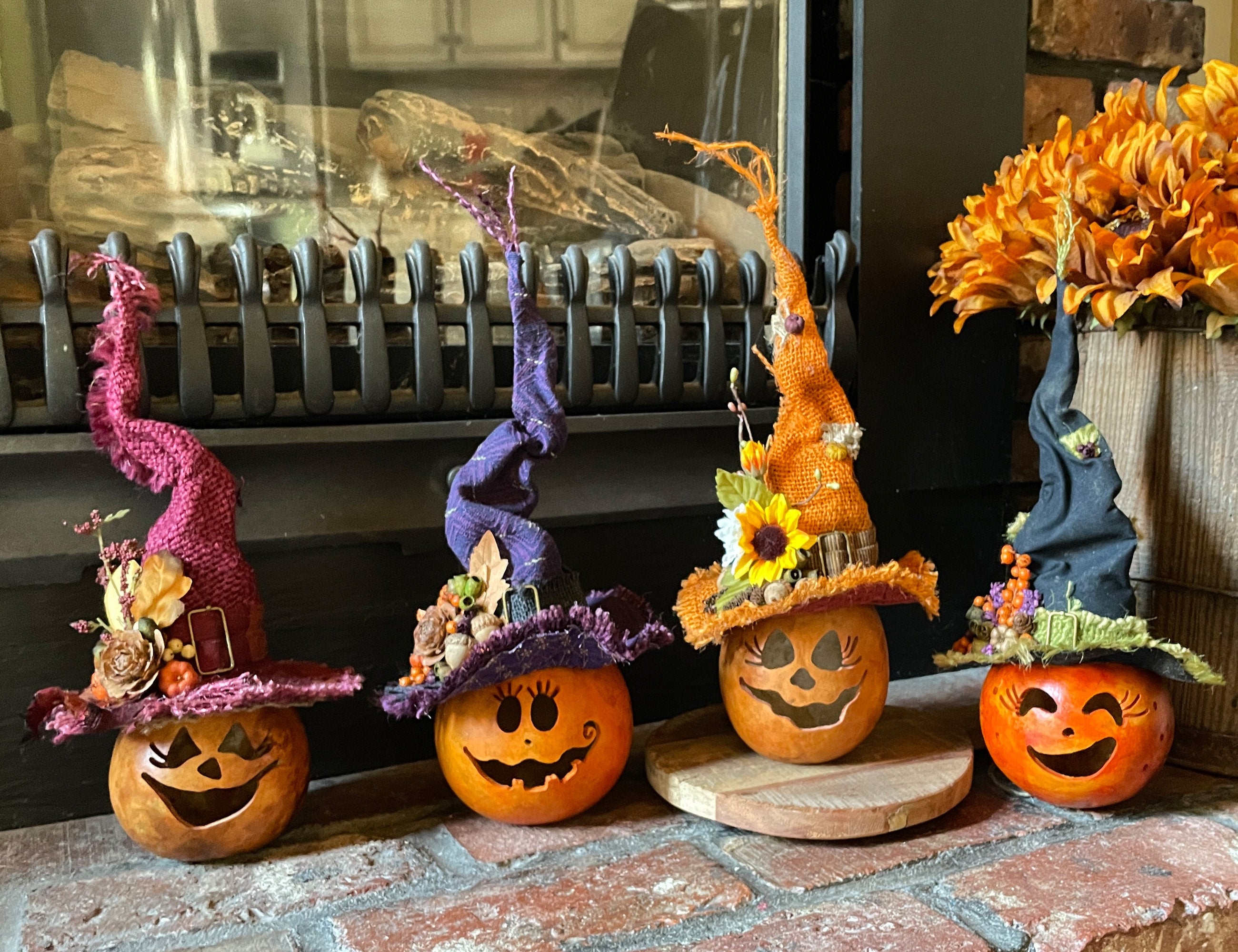 Decorative pumpkins with witch hats on a brick surface.