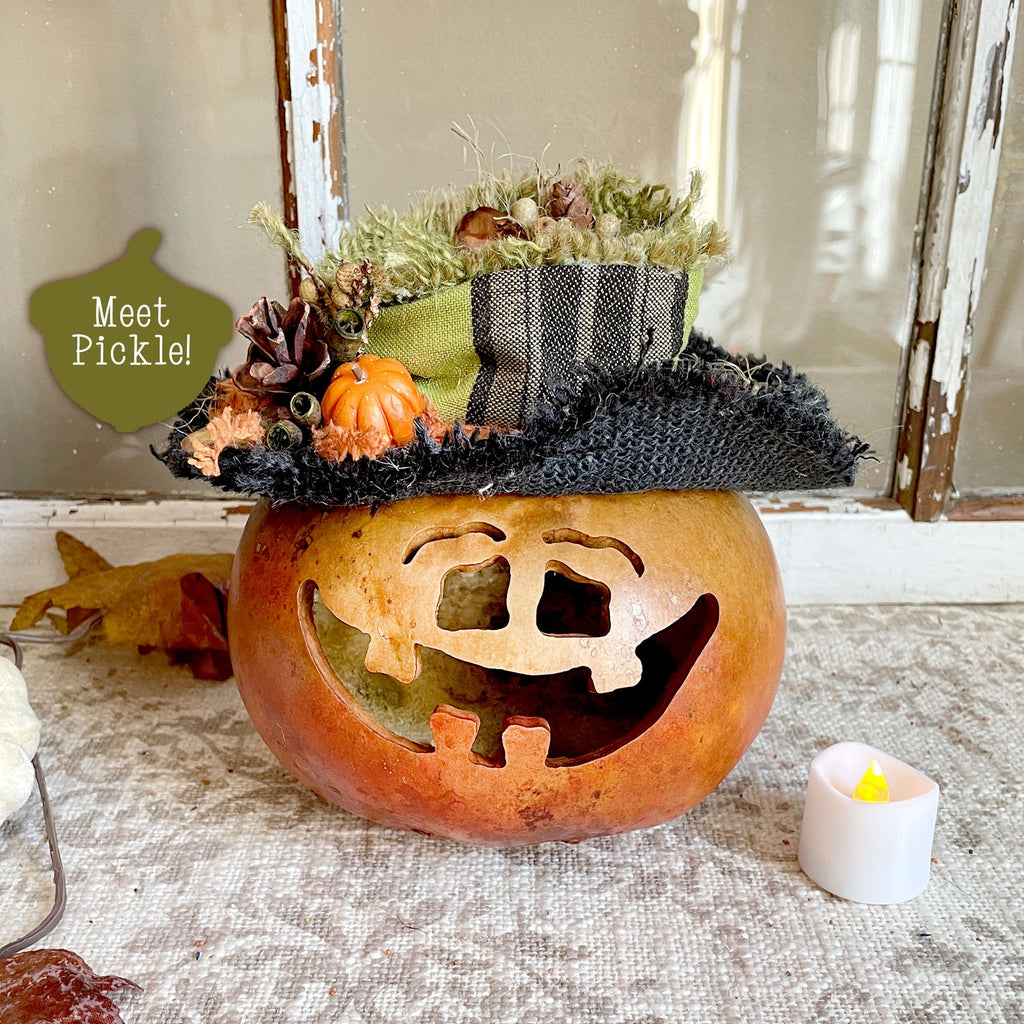 Decorative pumpkin with a witch hat and small pumpkins on a textured surface.