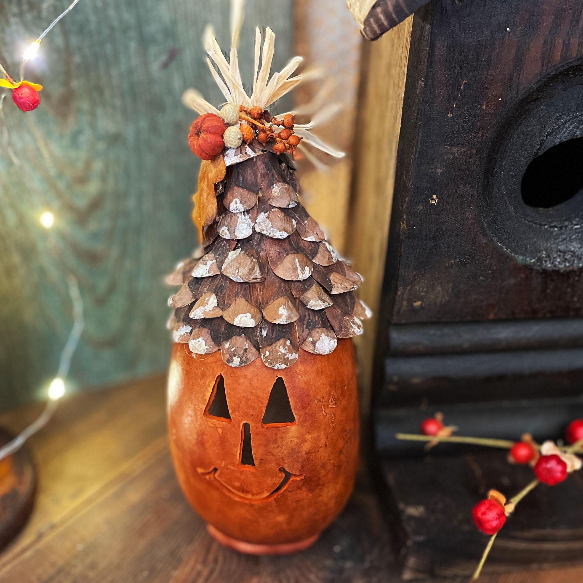 Decorative Halloween pumpkin with pine cone roof on a wooden surface
