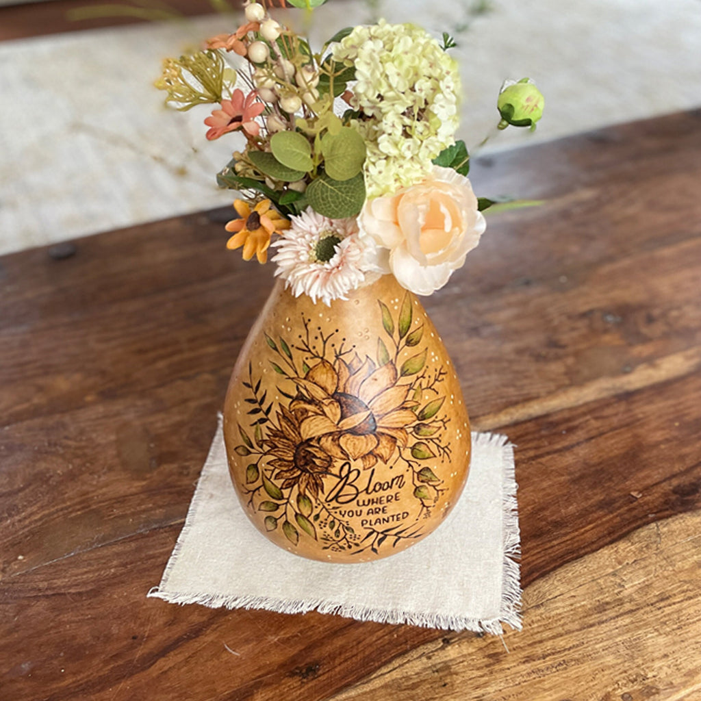 Decorative gourd vase with floral arrangement on a wooden surface