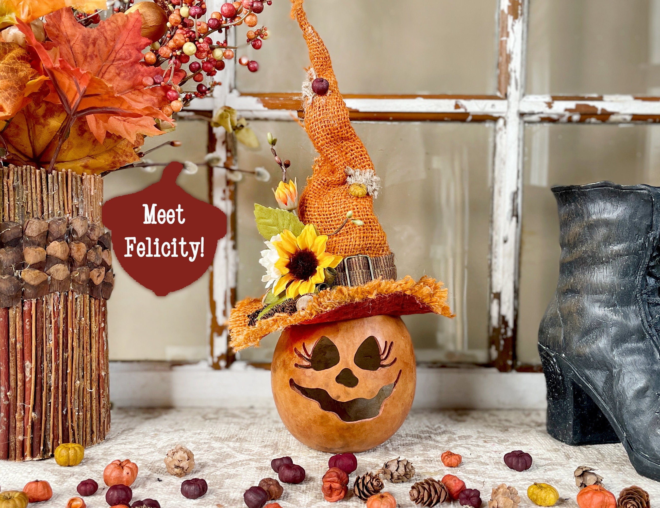 Decorative pumpkin with a witch hat and autumn leaves on a table.