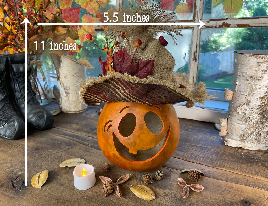 Decorative pumpkin with a hat on a wooden surface, surrounded by autumnal elements.