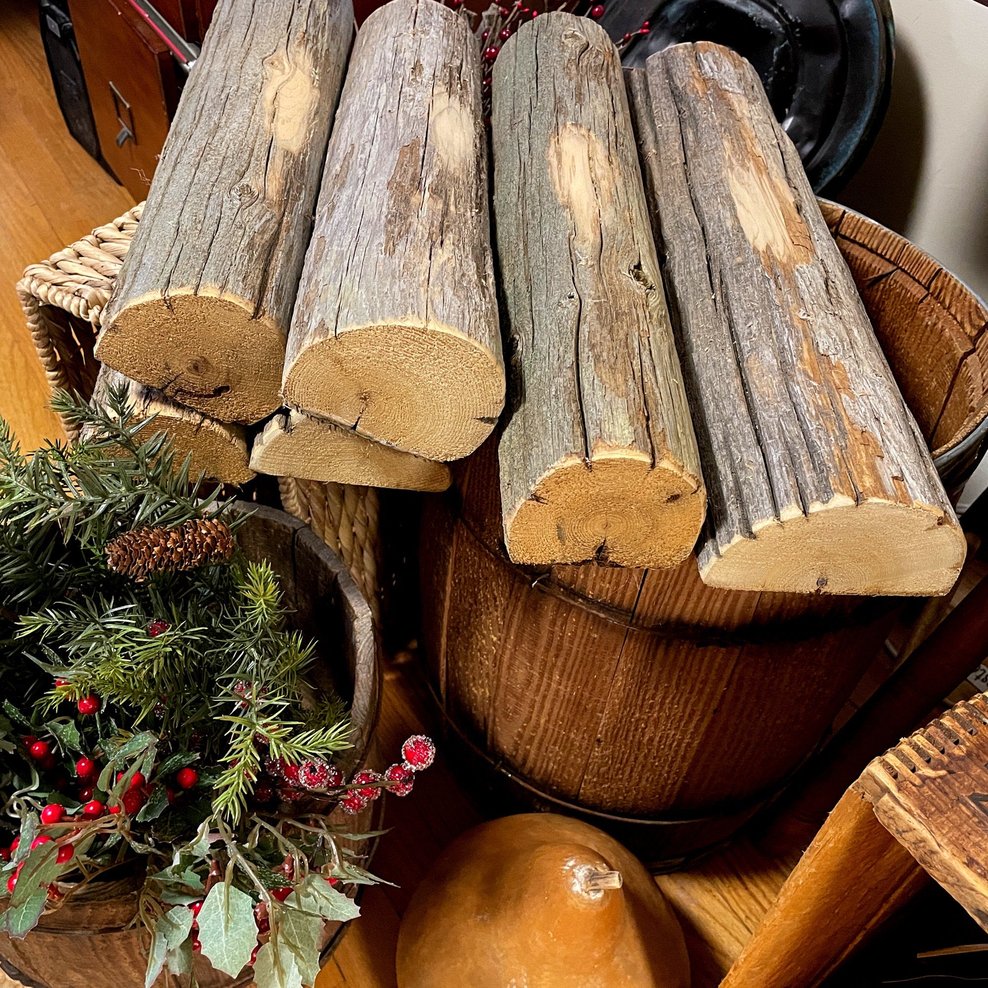 Wooden logs stacked on a wooden surface with Christmas decorations.