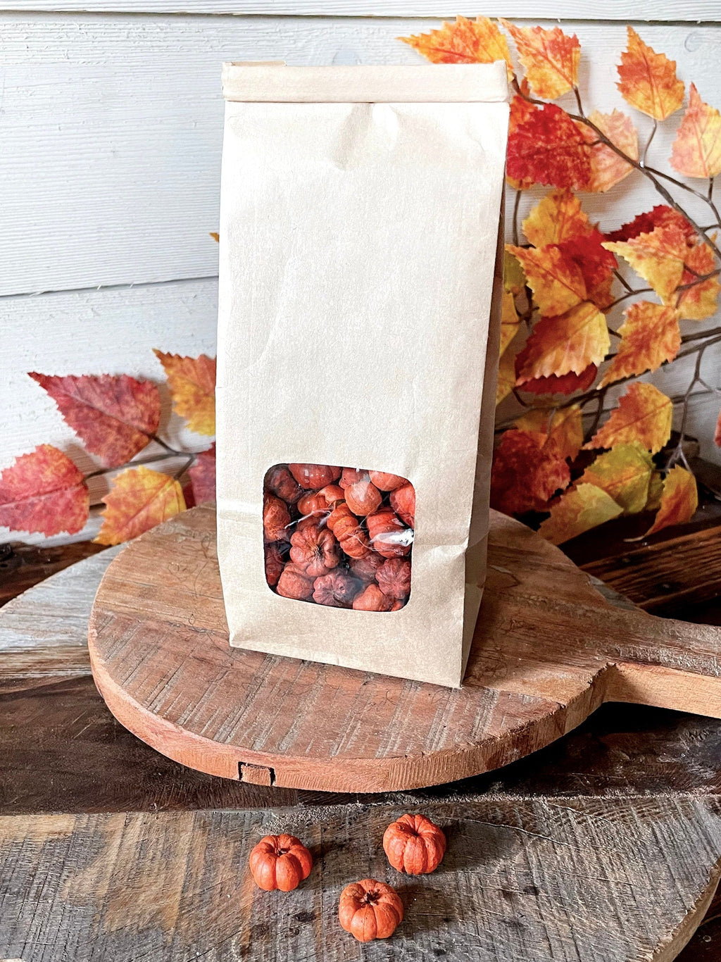 Bag of pumpkin pods on a wooden surface with autumn leaves in the background