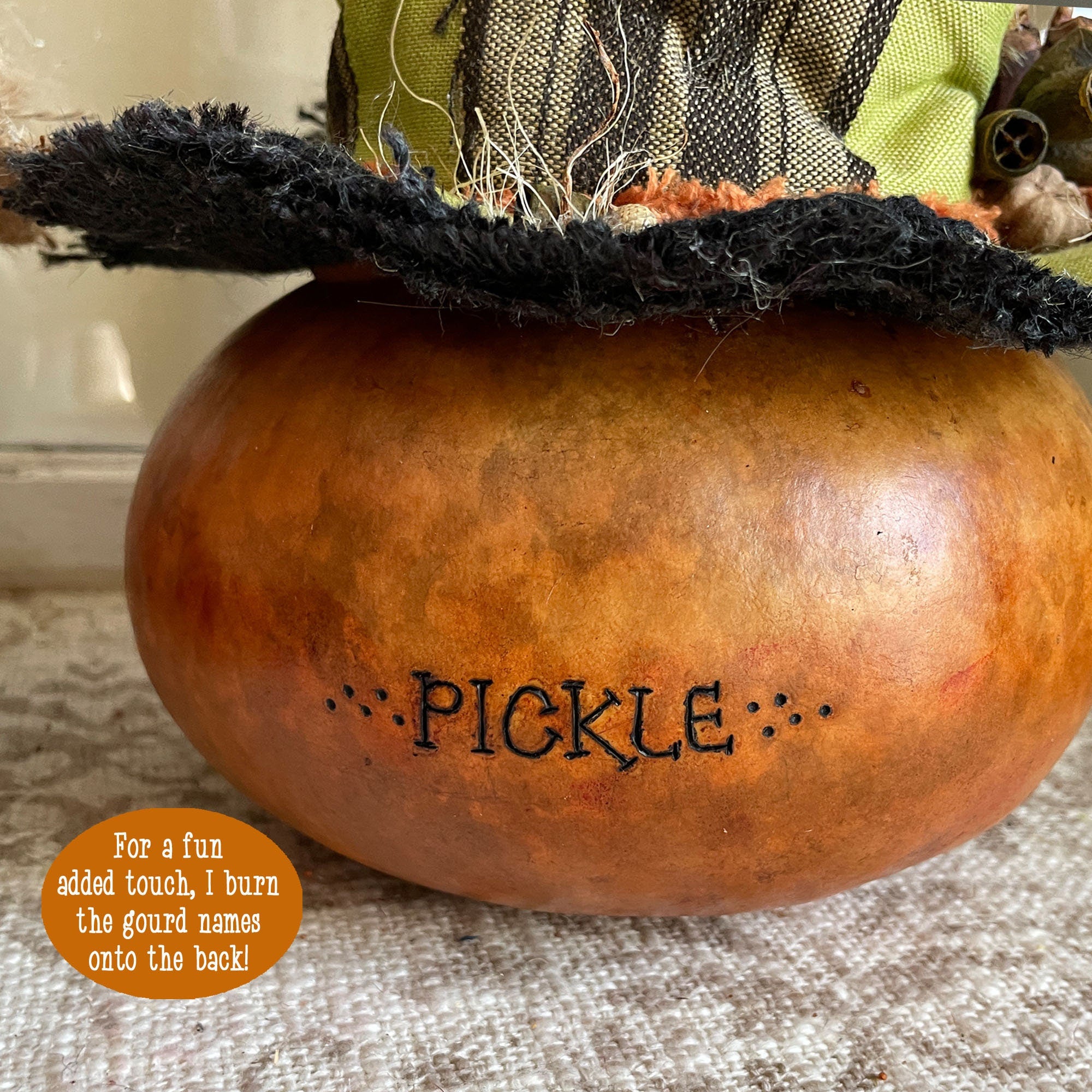 Decorative gourd with a black top labeled 'Pickle' on a textured surface.