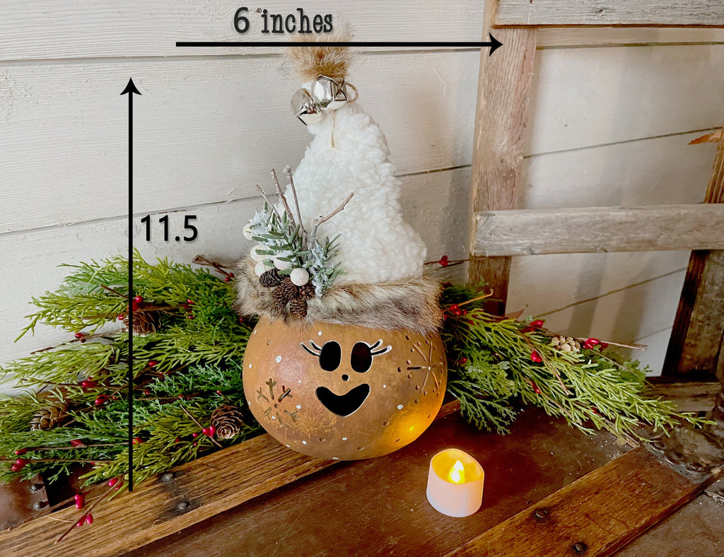 Decorative pumpkin with face and white top on a wooden surface with measurements shown.
