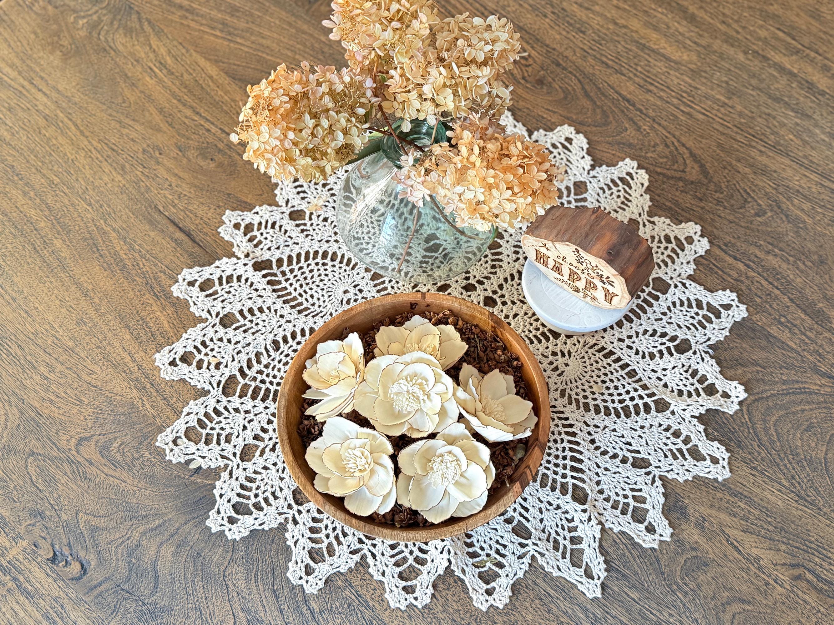 Decorative doily with a bowl of flowers on a wooden surface
