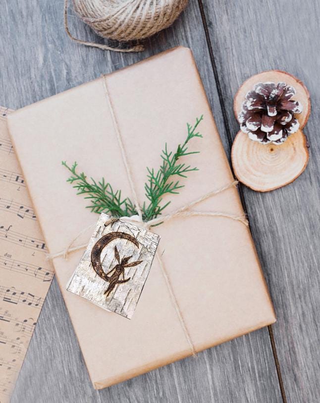 Natural Gift wrapped in kraft paper with greenery and a woodland fariy birch bark tag on it.