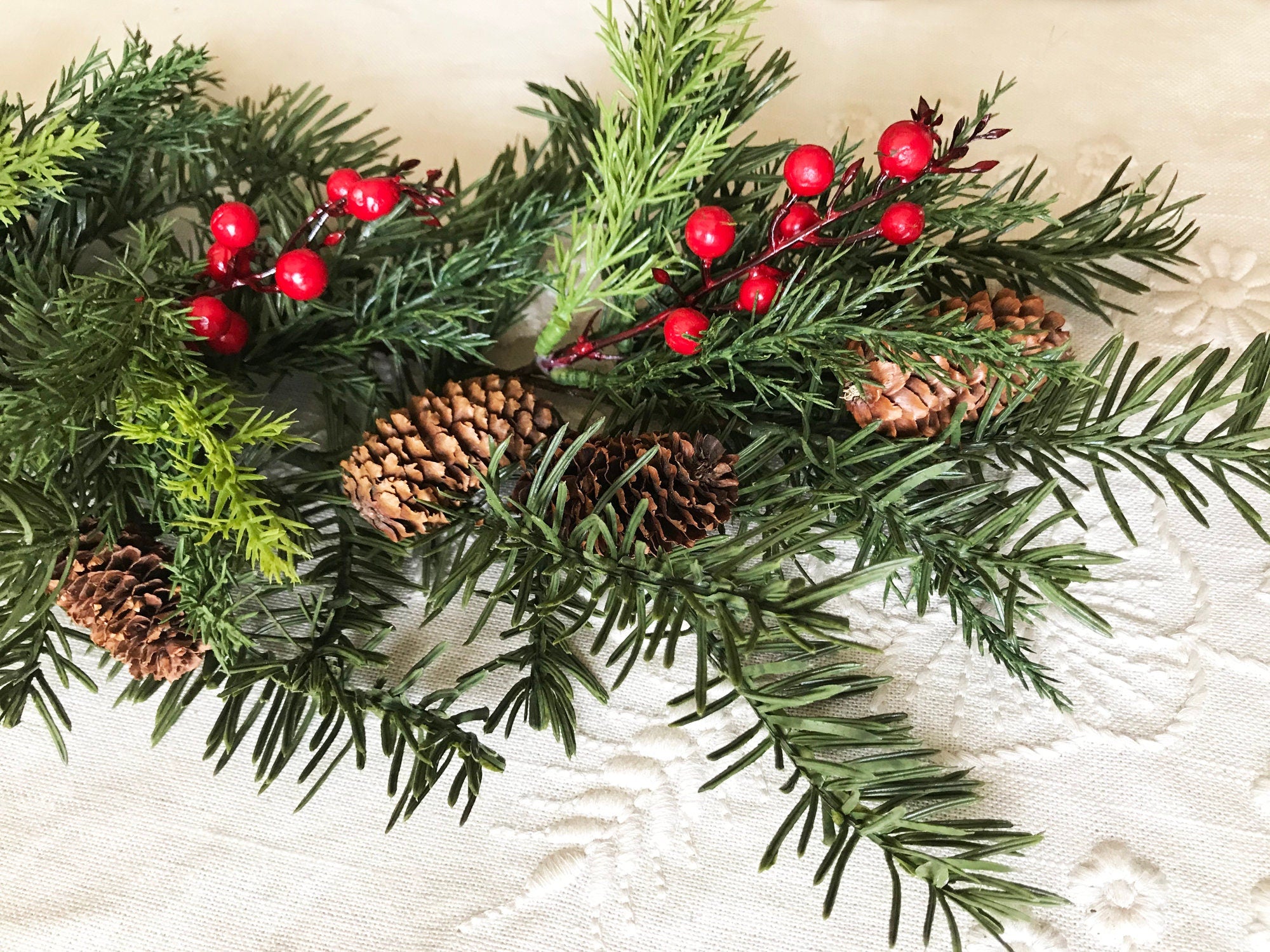 Christmas garland with red berries and pine cones on a textured surface