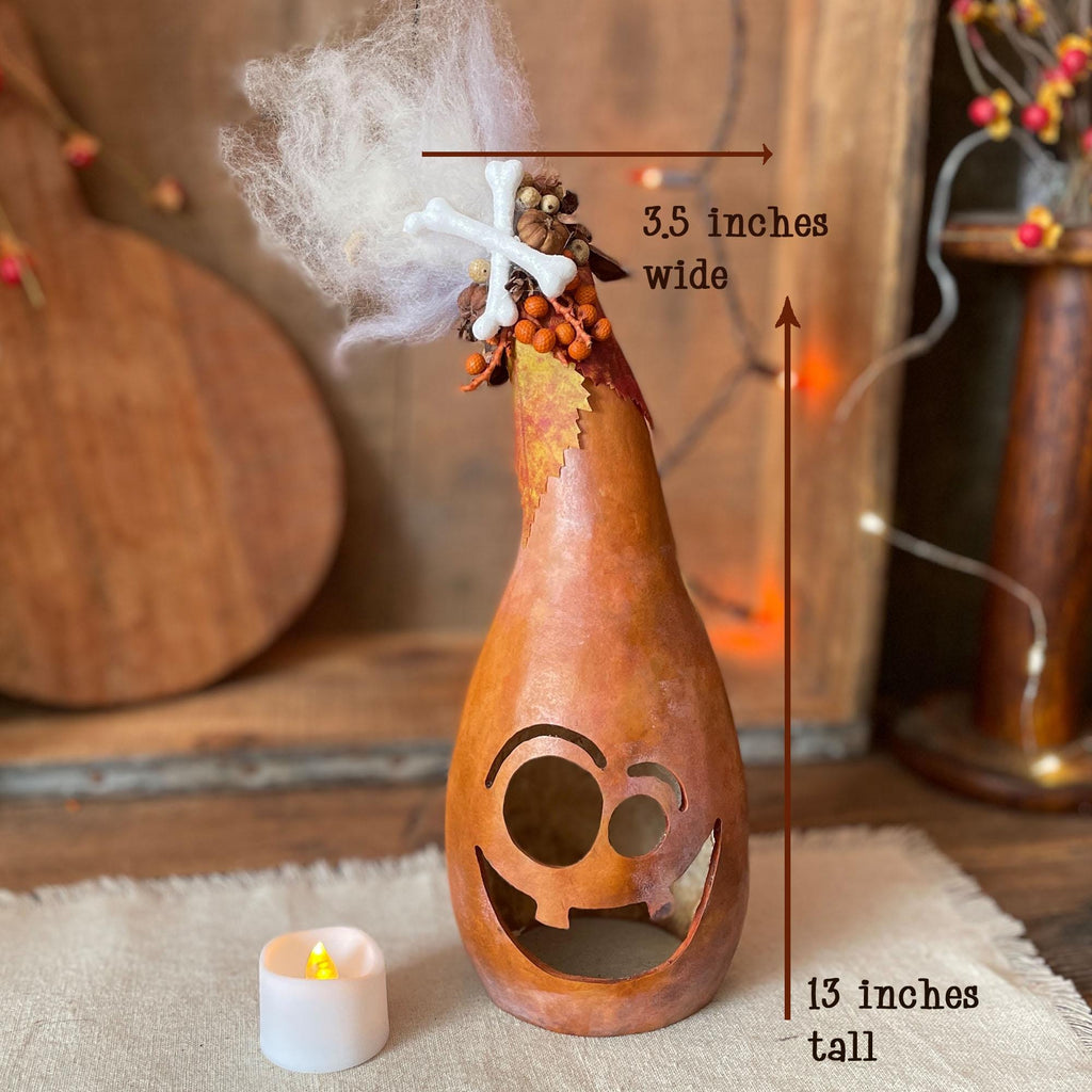 Decorative gourd with cut-out face, candle, and measurements on a rustic background