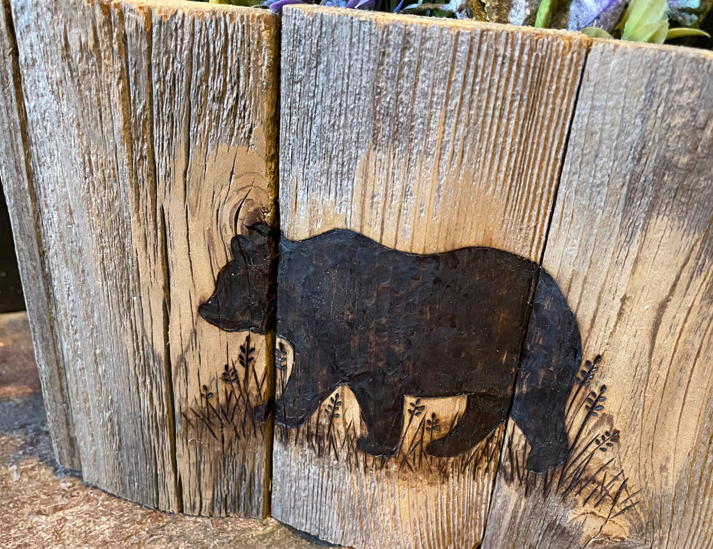 Wooden plaque with a bear silhouette cutout on a wooden background