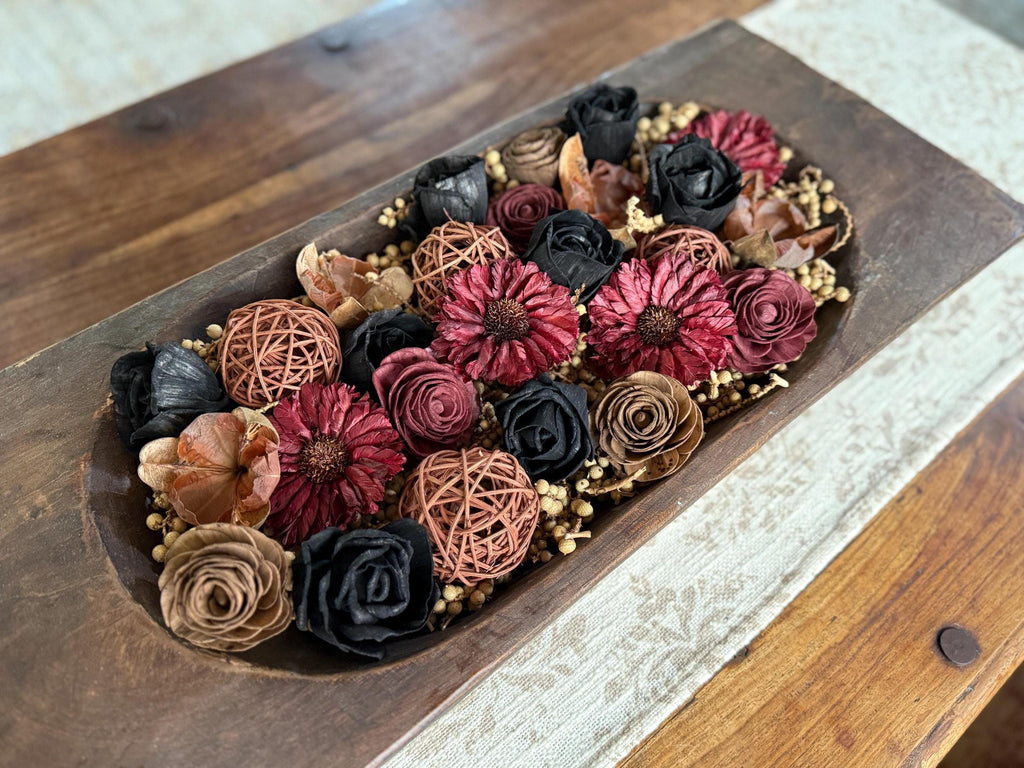 Decorative arrangement of artificial flowers in a wooden box on a wooden surface
