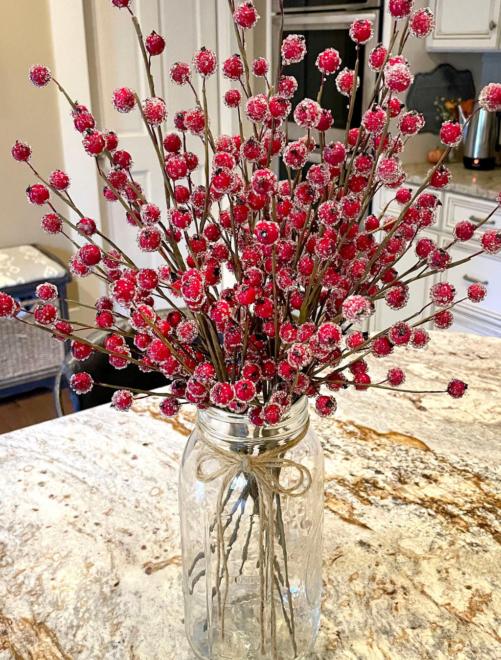 Bouquet of red and pink artificial flowers in a clear glass vase on a kitchen counter.