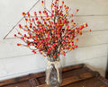 Mason jar with decorative berries on a wooden surface against a white paneled wall.