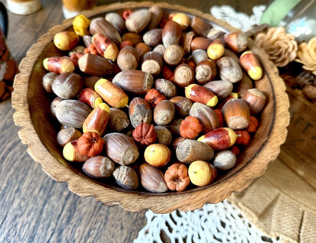 Autumn arrangement  in a wooden bowl filled with colorful acorns on a wooden surface