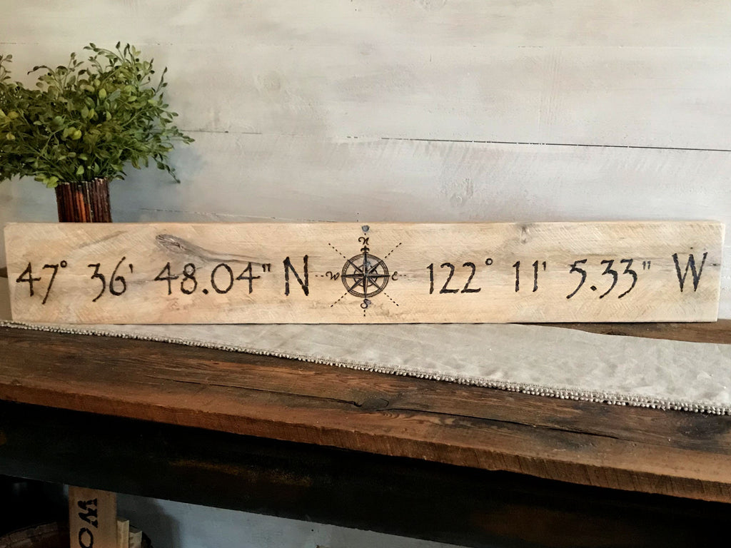 Wooden plaque with latitude and longitude coordinates on a wooden surface.