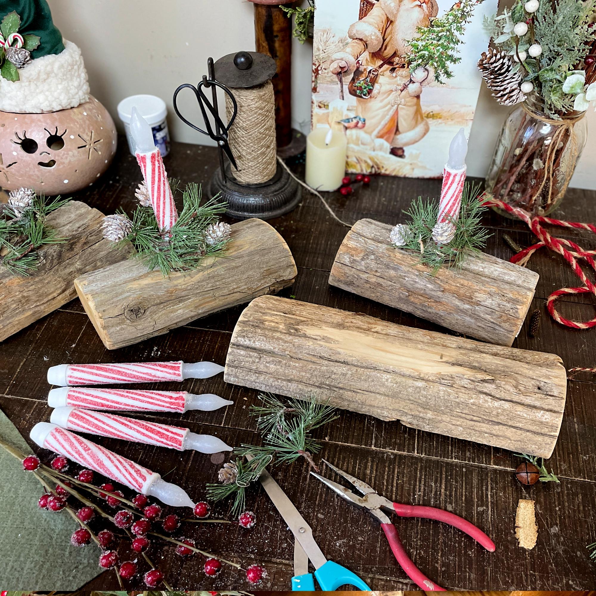 Decorative setup with wooden logs, candles, and Christmas decorations on a table.
