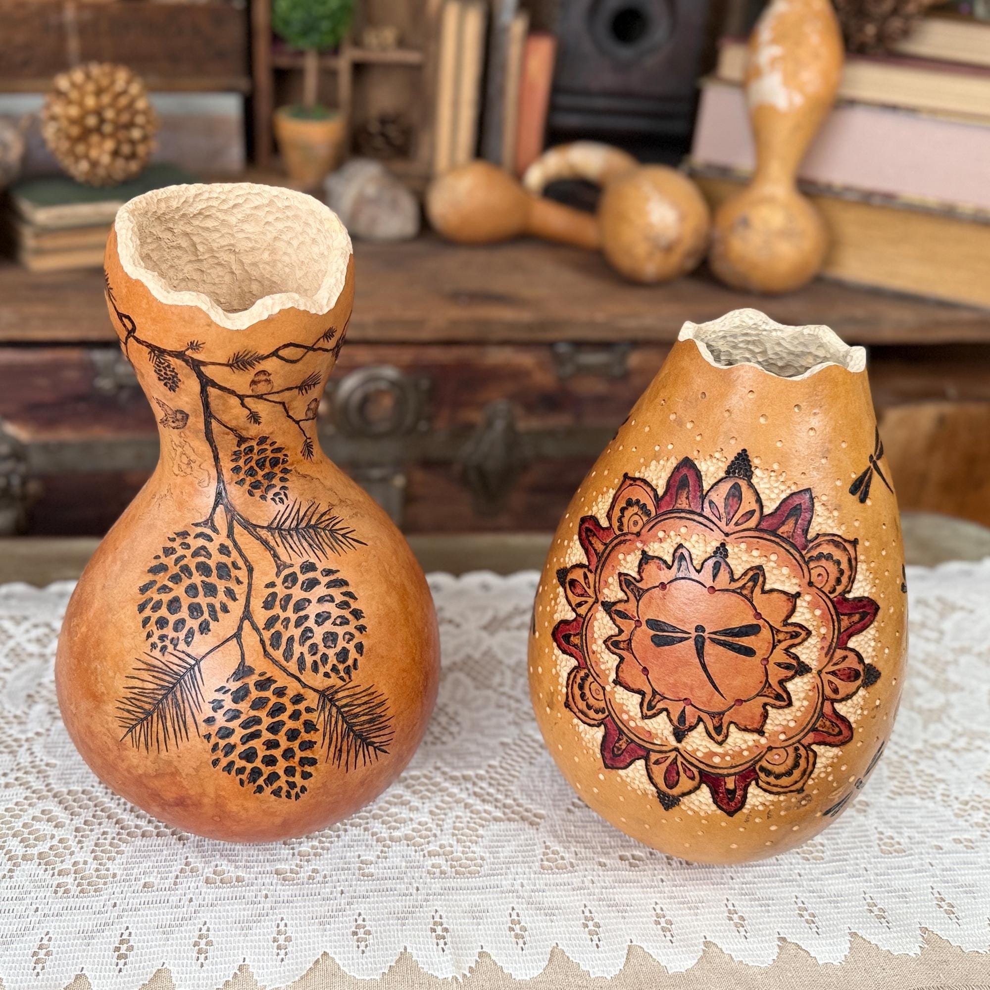 Two gourd vases with engraved designs on a lace tablecloth.