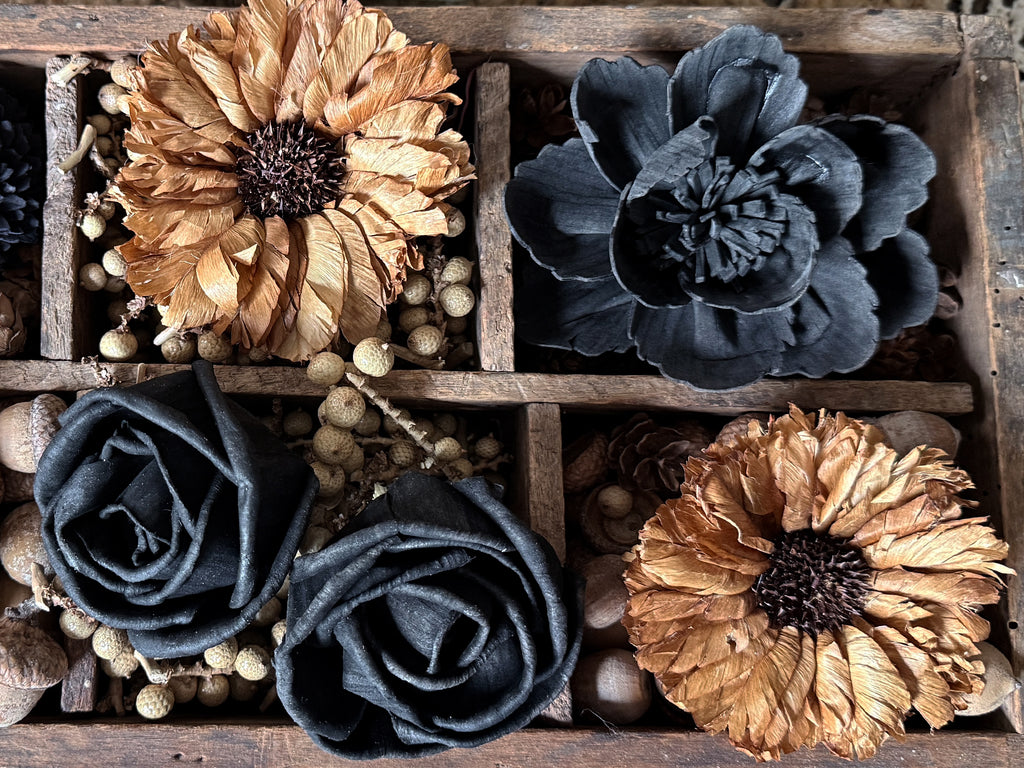 Decorative flower blossoms and wood roses in a wooden box with a rustic background