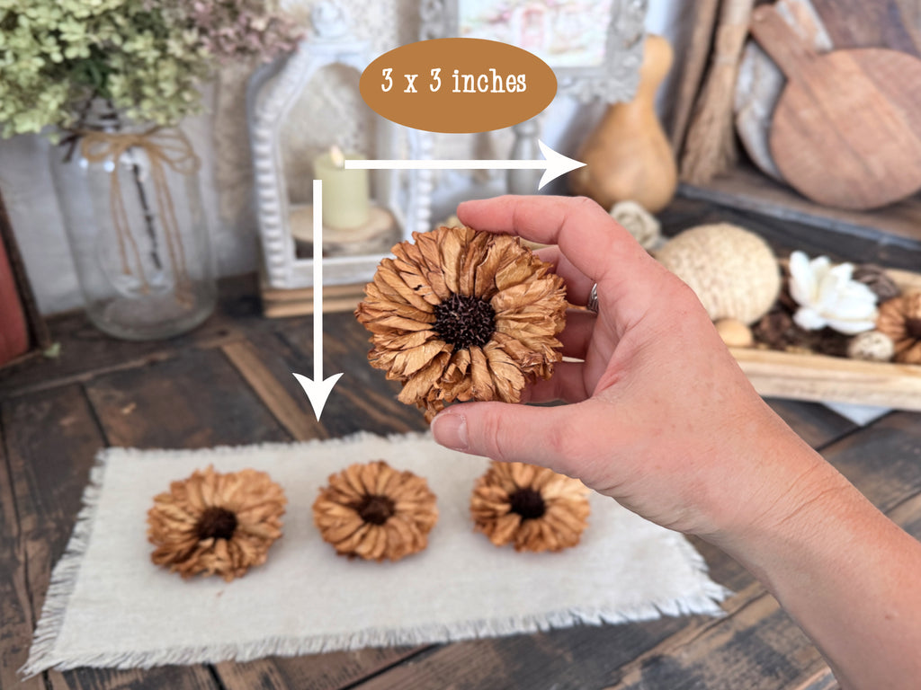 Hand holding a decorative sunflower with measurements on a wooden surface